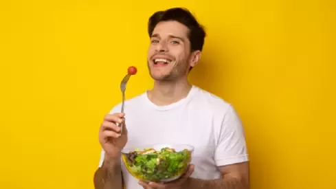 Hombre guapo comiendo una ensalada
