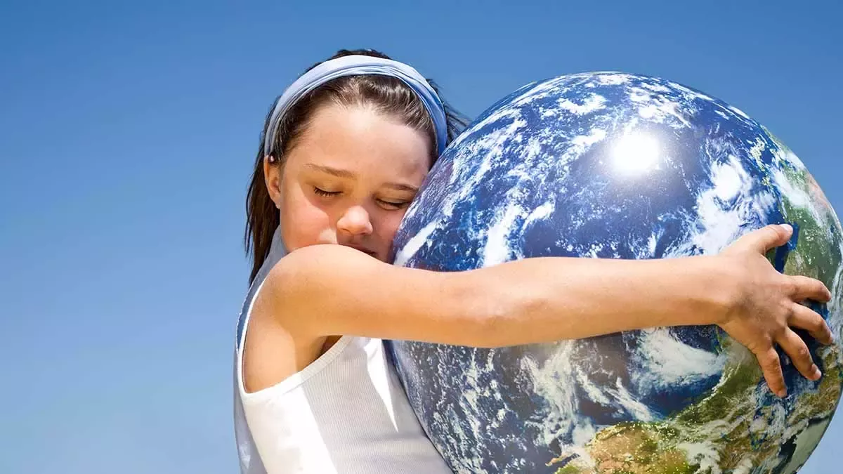 Niña abrazando planeta Tierra